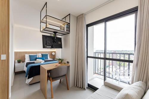 a bedroom with a bed and a desk and a window at Studio Resort Piscina Aquecida GYM Bem localizado in Curitiba