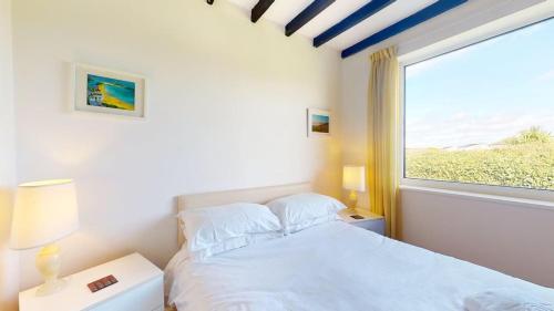a bedroom with a white bed and a window at C16 Treverbyn, Riviere Towans in Hayle