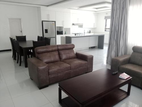 a living room with a couch and a table at LOMS Furnished Apartment - Luxurious Modern House near KKI Airport in Kenneth Kaunda International Airport