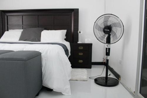 a bedroom with a bed with a fan and a chair at LOMS Furnished Apartment - Luxurious Modern House near KKI Airport in Kenneth Kaunda International Airport