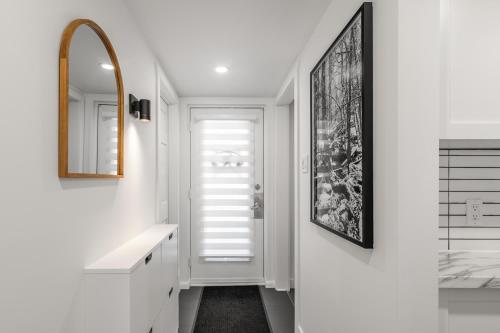 a white bathroom with a sink and a mirror at Hameau 26-43 Studio in Stoneham
