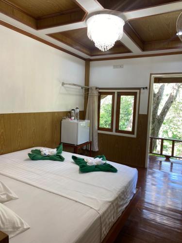 a bedroom with a large white bed with green bows at Mook Happy Bungalow in Koh Mook