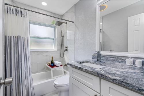 Un baño blanco con lavabo e inodoro. en Charming & Renovated Home 20 Minutes from Tampa, en Brandon