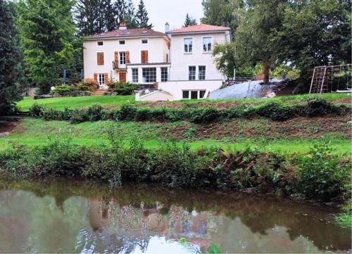 a large white house sitting next to a body of water at Domaine de la Brême 