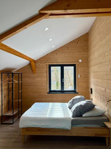 a bedroom with a bed in a wooden wall at Chalets Capucine ou Clochette 5P - SPA Privatif in Rochesson