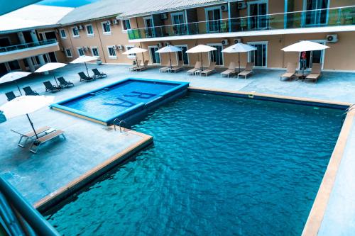 Royal Ambassador Hotel في Harbel: مسبح امام الفندق فيه كراسي ومظلات