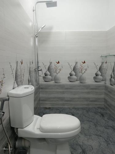 a bathroom with a toilet and a bunch of vases at Camellia Guest Inn in Ella