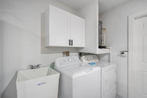 a white laundry room with a sink and a washing machine at Luxe Getaway w Pool, Games & Fun Vibes in Palm Harbor