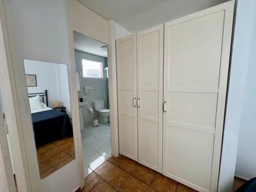 ein Badezimmer mit weißen Schränken und ein Schlafzimmer mit einem Bett in der Unterkunft De La Torre 1 in Guanarteme