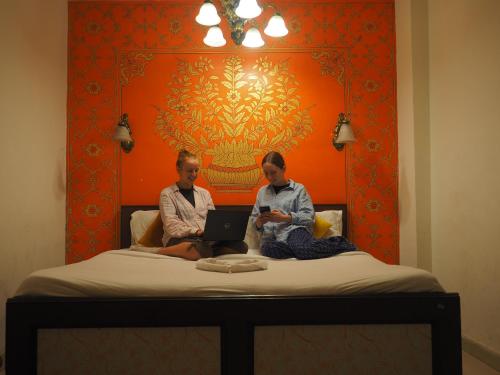 two men sitting on a bed with their laptops at Joey's Hostel in Jaipur