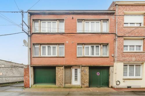 an old brick building with a green garage at Les Jardins, T3 avec parking -2 voitures, 8min à pied de la gare in Lens