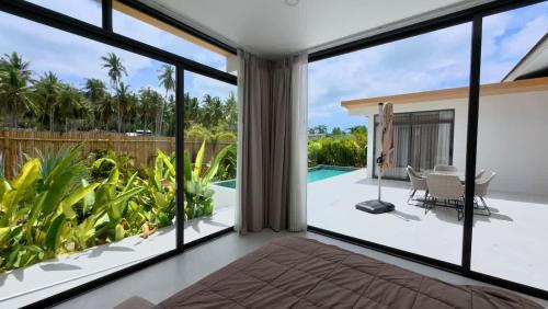 een woonkamer met grote ramen en een zwembad bij White Lotus Villa in Ban Madua Wan