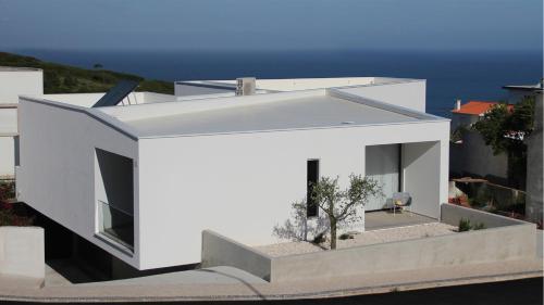 a white house with the ocean in the background at Villa Pescaria in Nazaré