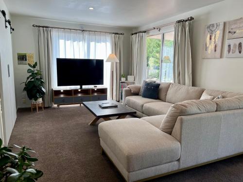 a living room with a couch and a flat screen tv at Sunshine cosy retreat in Hanmer Springs