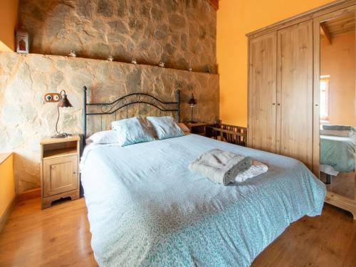 Tranquil Stay Near Luna River في Benllera: غرفة نوم بسرير وجدار حجري