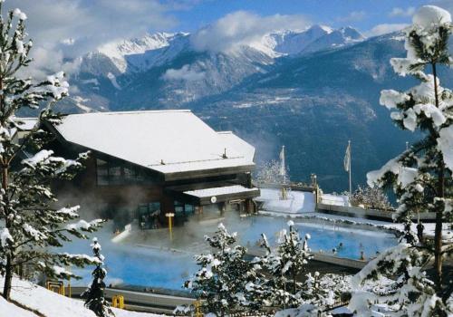 un edificio con una montaña cubierta de nieve en el fondo en Centre Thermal 2 chambres studio EV210, en Arni Alp