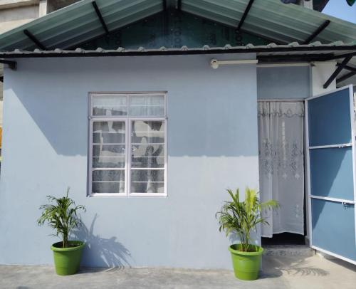una casa blanca con dos macetas delante de ella en B5 Homestay, en Shillong