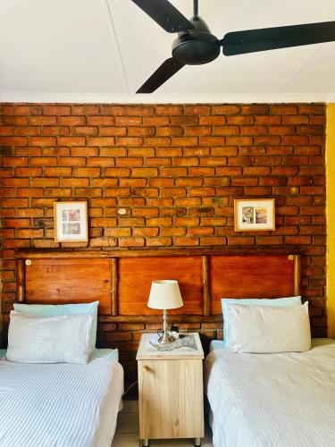 two beds in a room with a brick wall at Umhlanga Kruger in Marloth Park