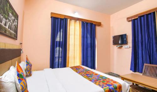 een hotelkamer met een bed en blauwe gordijnen bij Malti Guest House in Kullu Manali