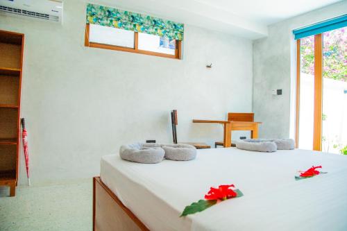 een slaapkamer met een wit bed met rode bloemen erop bij Bahari View in Jambiani