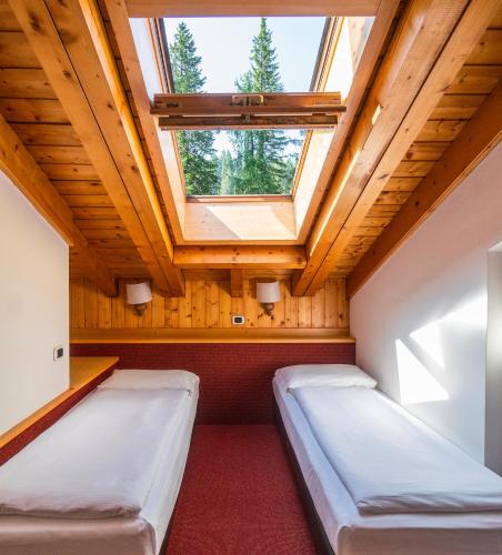 two beds in a room with a skylight at Ambiez Residencehotel in Madonna di Campiglio