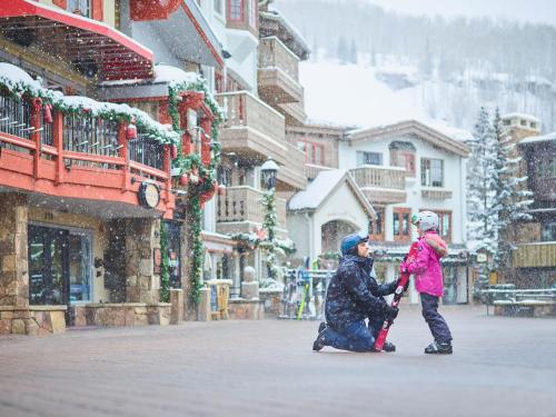 a man and woman walking down a street in the snow at The Sebastian - Vail in Vail