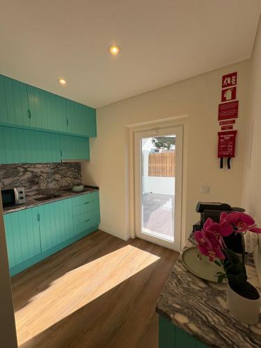 une cuisine avec des armoires vertes et un comptoir avec une fenêtre dans l'établissement Casa das Orquídeas Meco, à Sesimbra