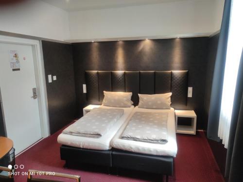 a bedroom with a large bed with a black headboard at Hotel Corveyer Hof in Höxter