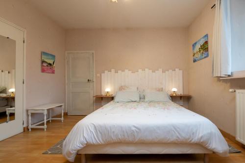 Un dormitorio con una gran cama blanca con dos lámparas. en Manoir De Gourvinec - Chambre, en Saint-Nolff