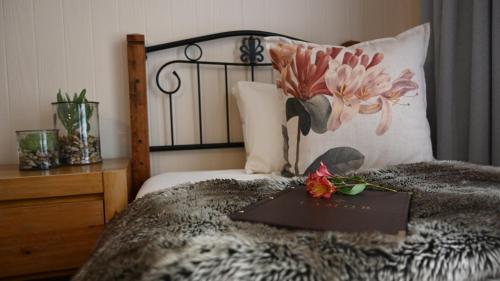 LUXURY FAMILY EN-SUITE ROOM @ 4 STAR GUEST HOUSE في ميدلبرغ: كتاب على سرير عليه زهرة