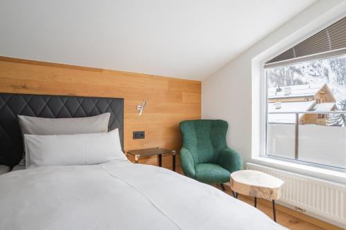 a bedroom with a bed and a green chair at Black Summit Samnaun Boutique Hotel in Samnaun