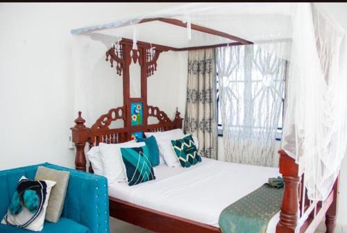 Pazuri Homes في متوابا: غرفة نوم بها سرير مظلة وأريكة زرقاء