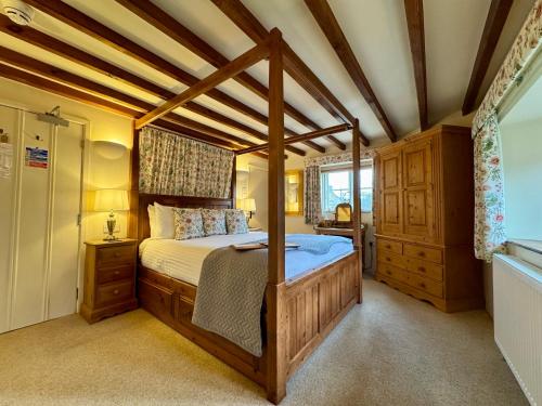 een slaapkamer met een hemelbed in een kamer bij Guiting Guest House in Guiting Power