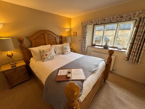een slaapkamer met een bed met een boek erop bij Guiting Guest House in Guiting Power
