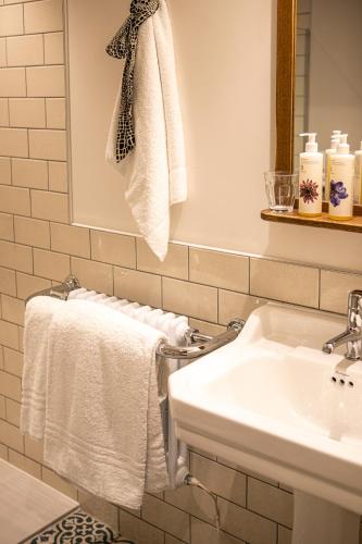 a white bathroom with a sink and towels at The Filly Inn in Brockenhurst