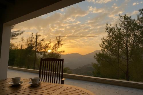 Uma mesa com duas xícaras de café e vista para as montanhas. em Gazingstars Cottages Agridia 