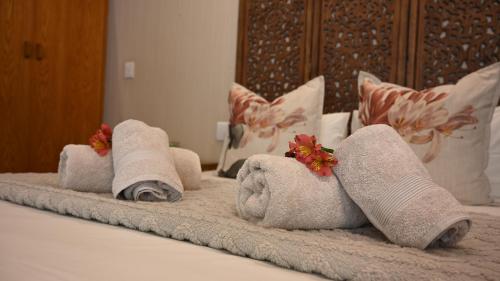 LUXURY FAMILY EN-SUITE ROOM @ 4 STAR GUEST HOUSE في ميدلبرغ: صف من المناشف موضوعة على سرير