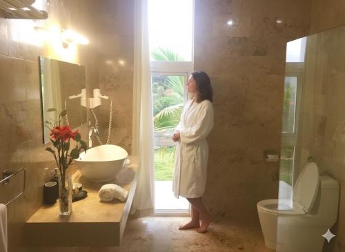 Las Galeras Village Ecolodge في لاس غاليراس: امرأة ترتدي رداء حمام وتقف في الحمام