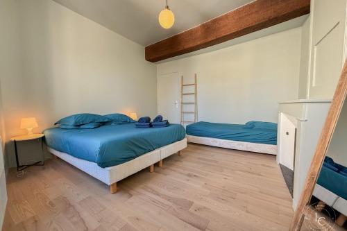 1 dormitorio con 2 camas con sábanas azules y escalera en L'Ecrin Balgentien - A deux pas de la Loire et du Centre, en Beaugency