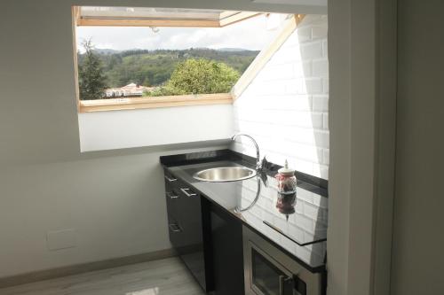 una pequeña cocina con fregadero y ventana en Pensión El Ansar en Cartes