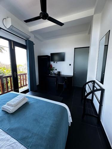 a bedroom with a large bed with a blue blanket at Lucky Monkey Inn and Restaurant in Weligama