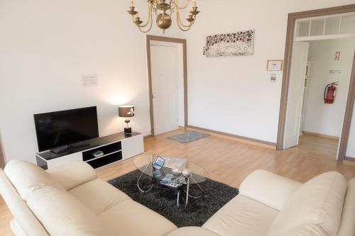 a living room with a white couch and a tv at Afternoon Desire in Ponta Delgada