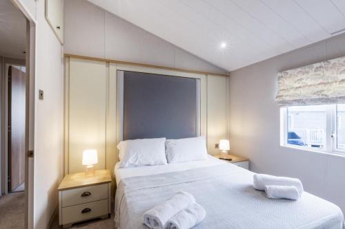 a bedroom with a bed with two towels on it at Lodge 15 at Landscove Holiday Park in Brixham