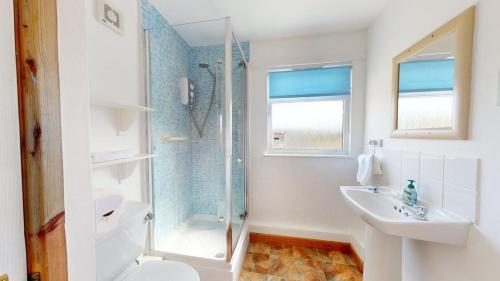 a white bathroom with a shower and a sink at C23 Wilmar, Riviere Towans in Hayle