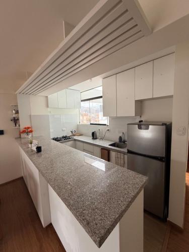 une cuisine avec des armoires blanches et un réfrigérateur en acier inoxydable dans l'établissement SB5 Apartment, à Cusco