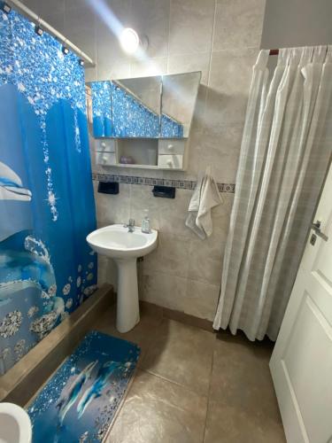 een badkamer met een wastafel en een blauw douchegordijn bij Casita en general Pacheco in General Pacheco