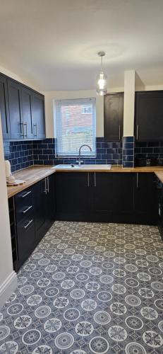 a kitchen with black cabinets and a tile floor at Driftwood Cottage in Redcar