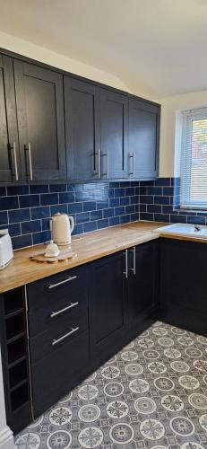 a kitchen with black cabinets and blue tiles at Driftwood Cottage in Redcar