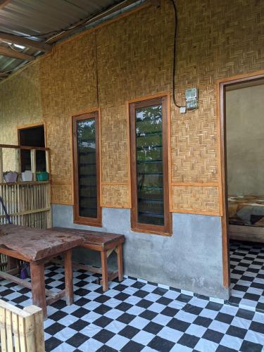 a room with a wooden table and a checkered floor at Local Garden Homestay in Masbagik