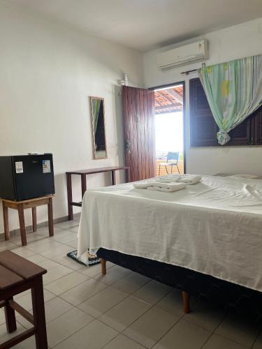 a bedroom with a bed and a table and a window at Pousada Rosa Mistica in Paracuru